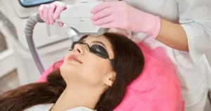 Woman receiving IPL therapy on her forehead to address sun damage and pigmentation, wearing protective eyewear.