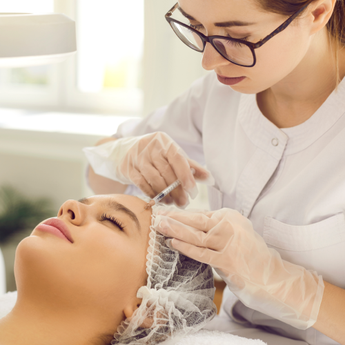 Clinician injecting Sculptra filler into woman's face at Enhanced Wellness clinic.