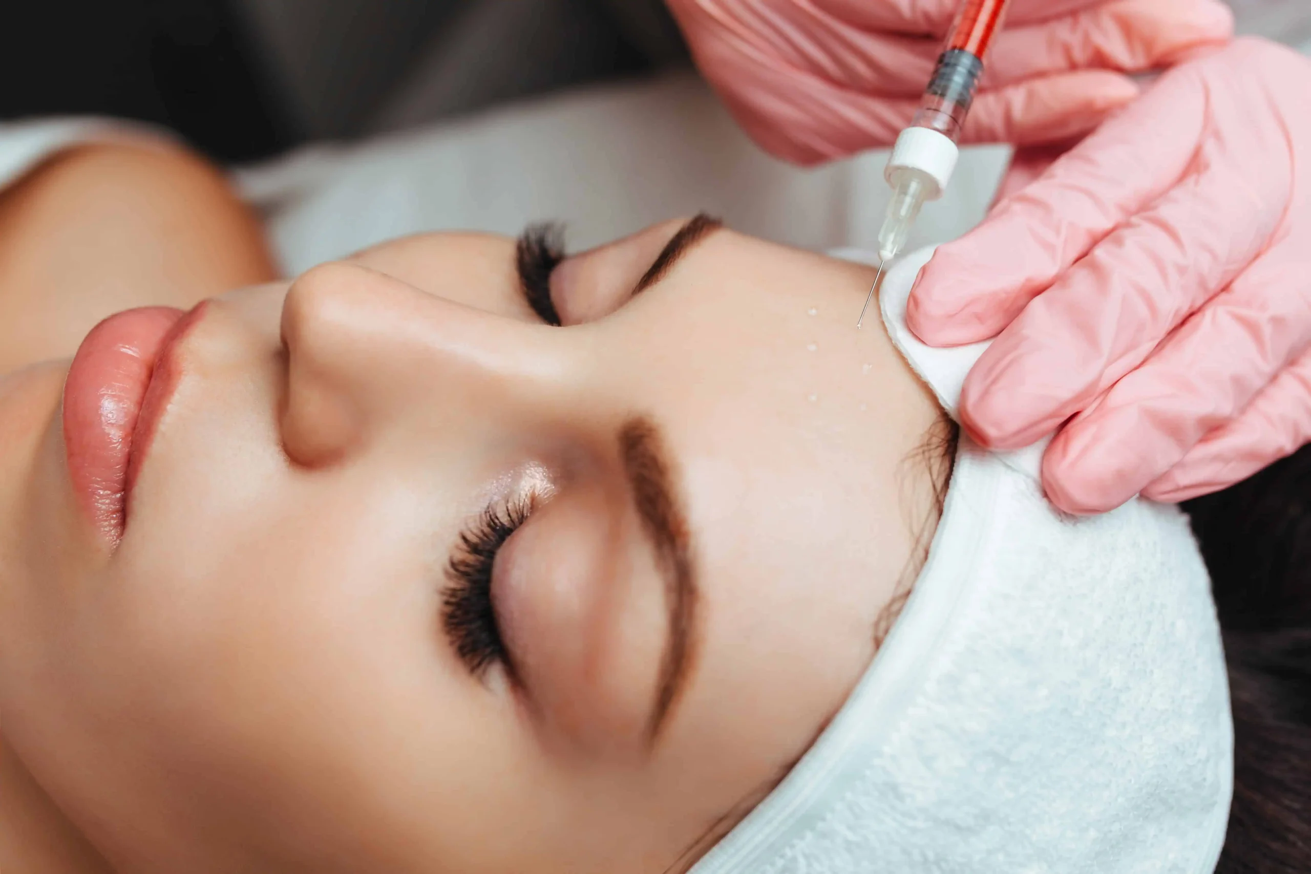 Clinician injecting Jeuveau neurotoxin in woman's forehead at Enhanced Wellness in Derby, KS.